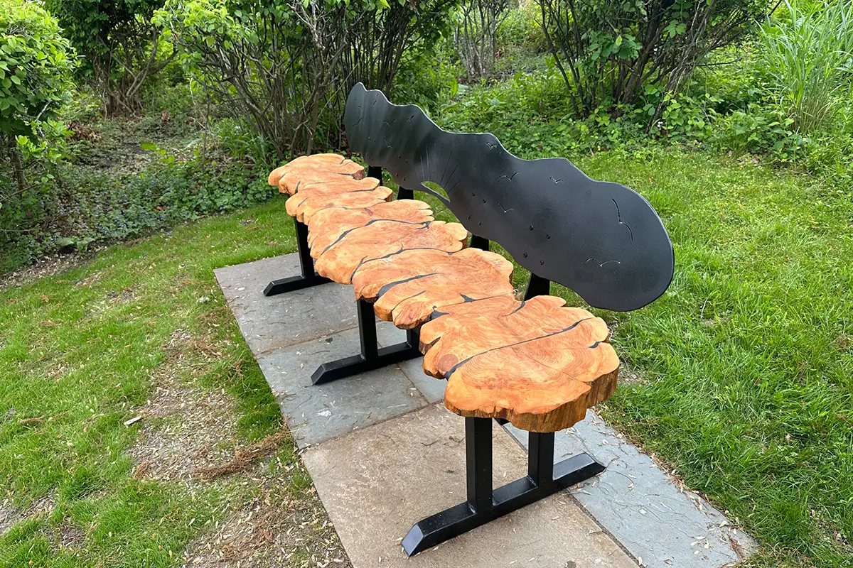 Outdoor bench with guitar-shaped backrest and tree slice seats.