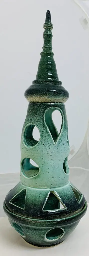 Green ceramic vase with unique cut-out designs and glossy finish.
