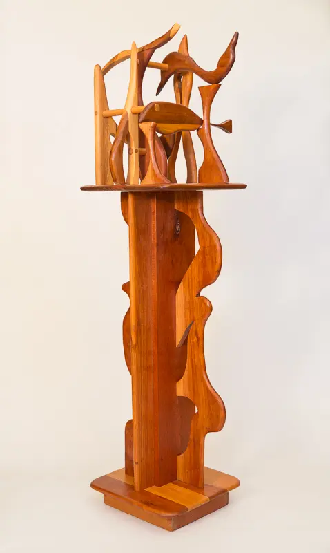 Tall wooden sculpture with intricate cutouts and geometric shapes.