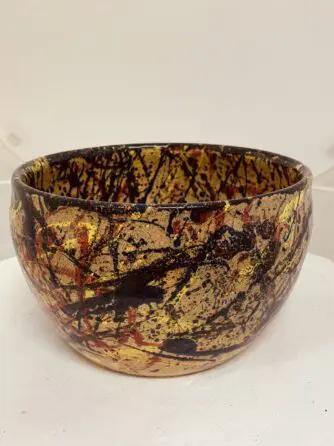 A ceramic bowl with abstract, splattered paint design in brown and black.