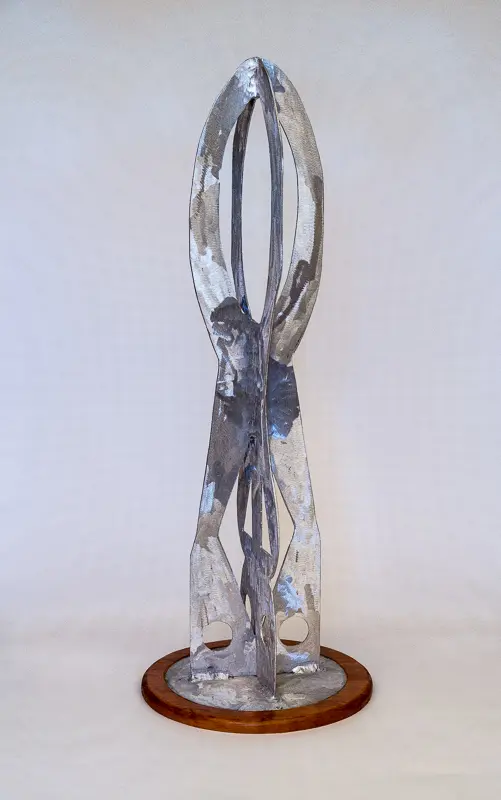 Abstract metallic sculpture with elongated forms on a white surface.