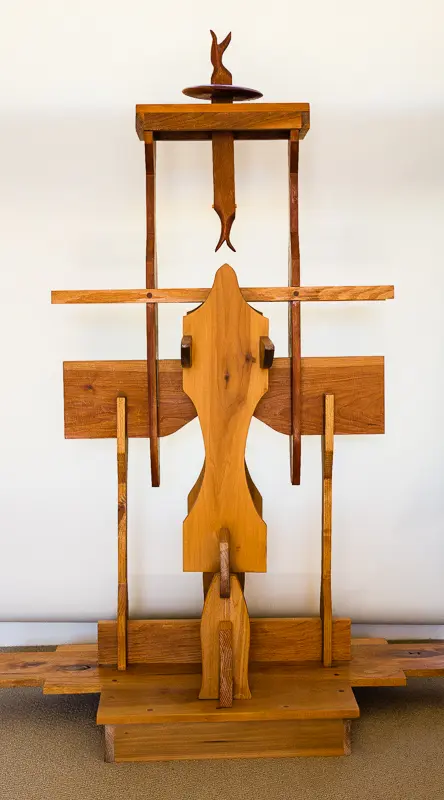 Wooden abstract sculpture mounted on a white wall.