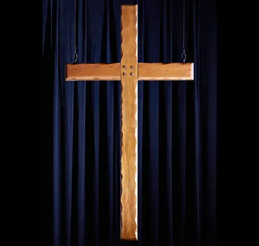 Wooden cross against a dark blue curtain backdrop.