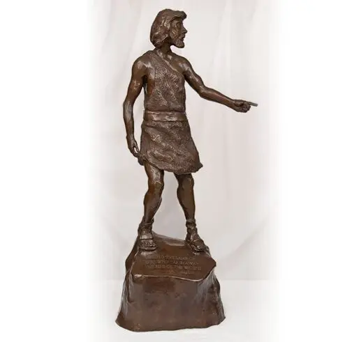 Bronze statue of a man in ancient attire standing on a rock.