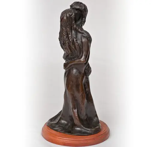 Bronze sculpture of a woman holding a child, standing on a wooden base.