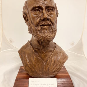 A bronze bust of a bearded man on a wooden base.