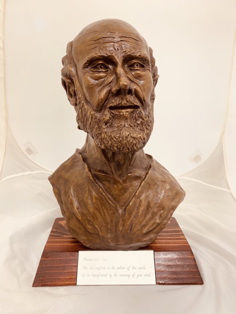 A bronze bust of a bearded man on a wooden base.