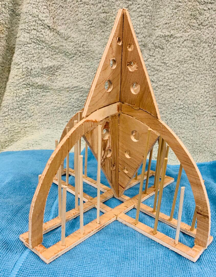 Wooden geometric sculpture with intricate cutouts on a blue cloth.