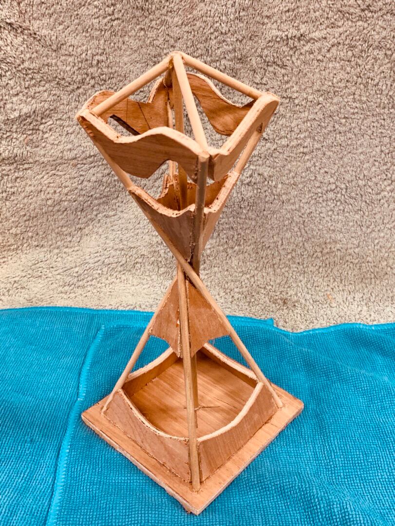 Wooden geometric sculpture with triangular shapes and a natural finish.