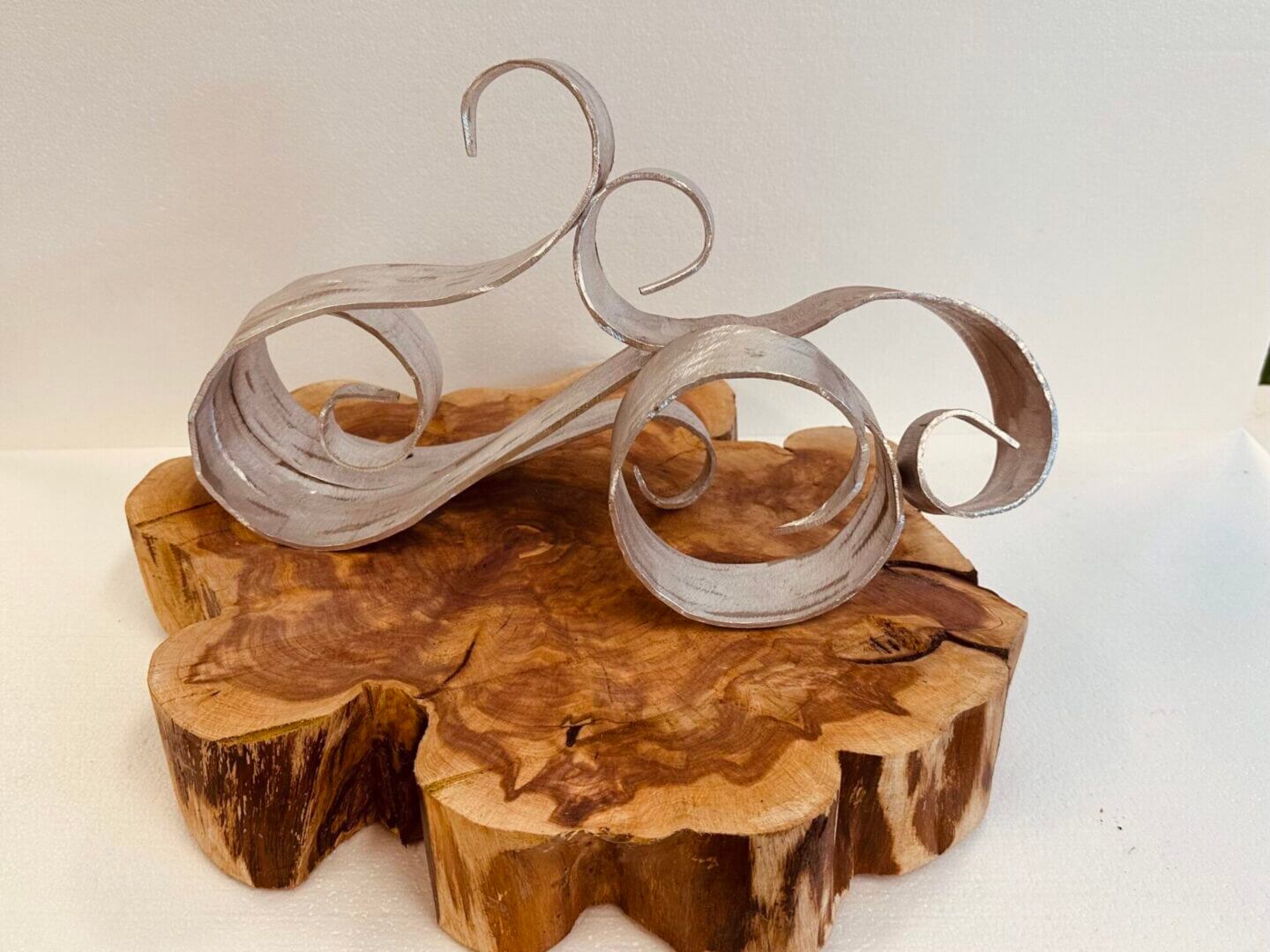 Elegant wooden sculptures with flowing, ribbon-like curves on a natural wood base.