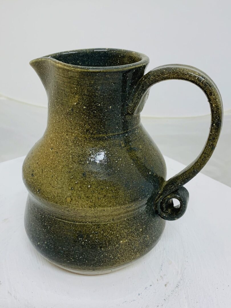 A rustic ceramic jug with a handle and spout.