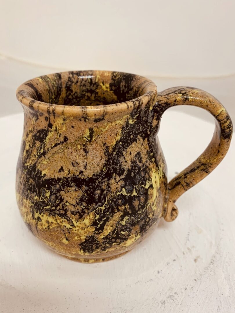 A marbled ceramic mug with earthy tones and a rounded handle.