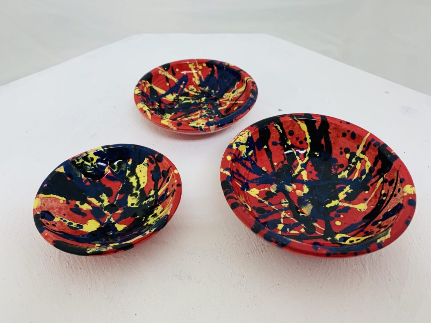 Three decorative bowls with vibrant red, yellow, and black abstract patterns.