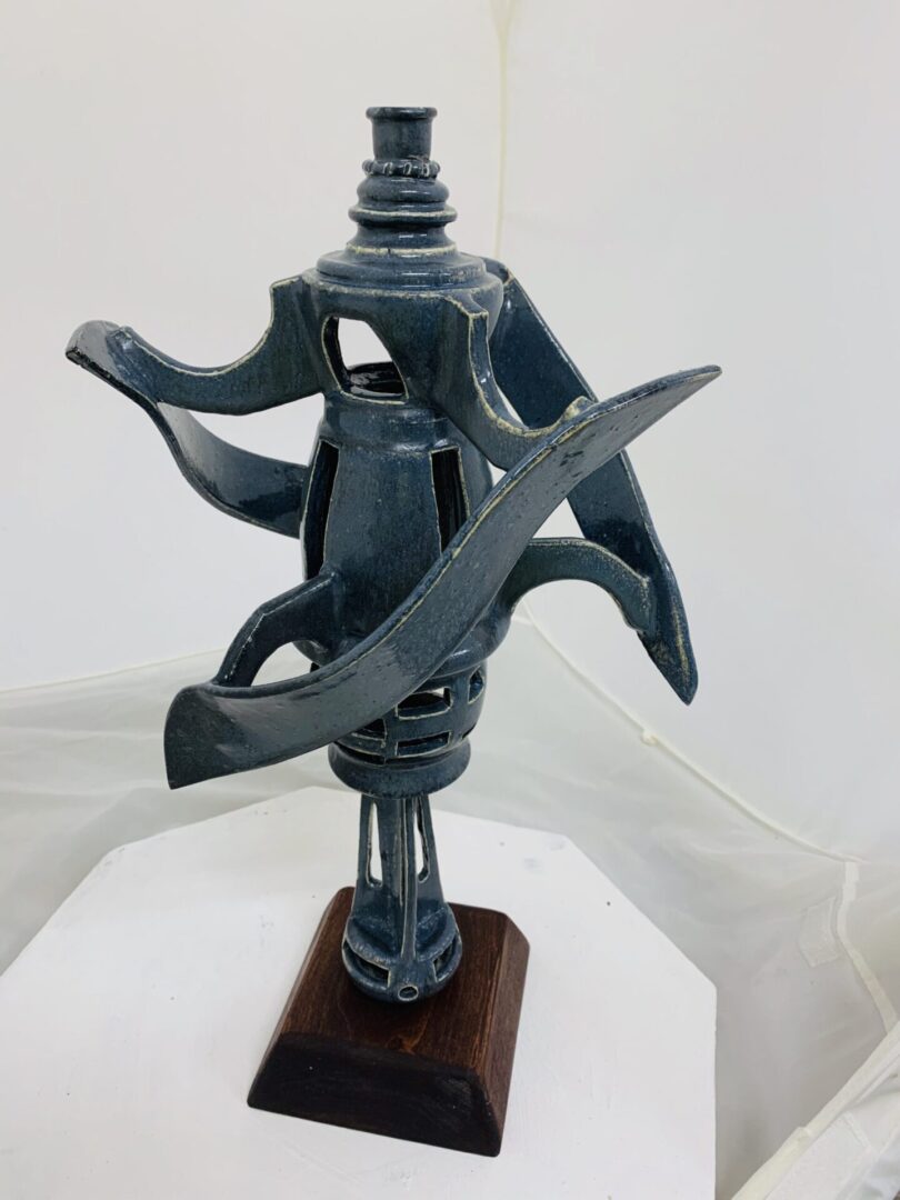 Abstract metal sculpture with dynamic curved elements on a wooden base.