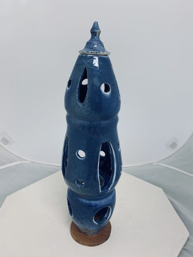 Blue ceramic sculpture with multiple holes and a unique shape.
