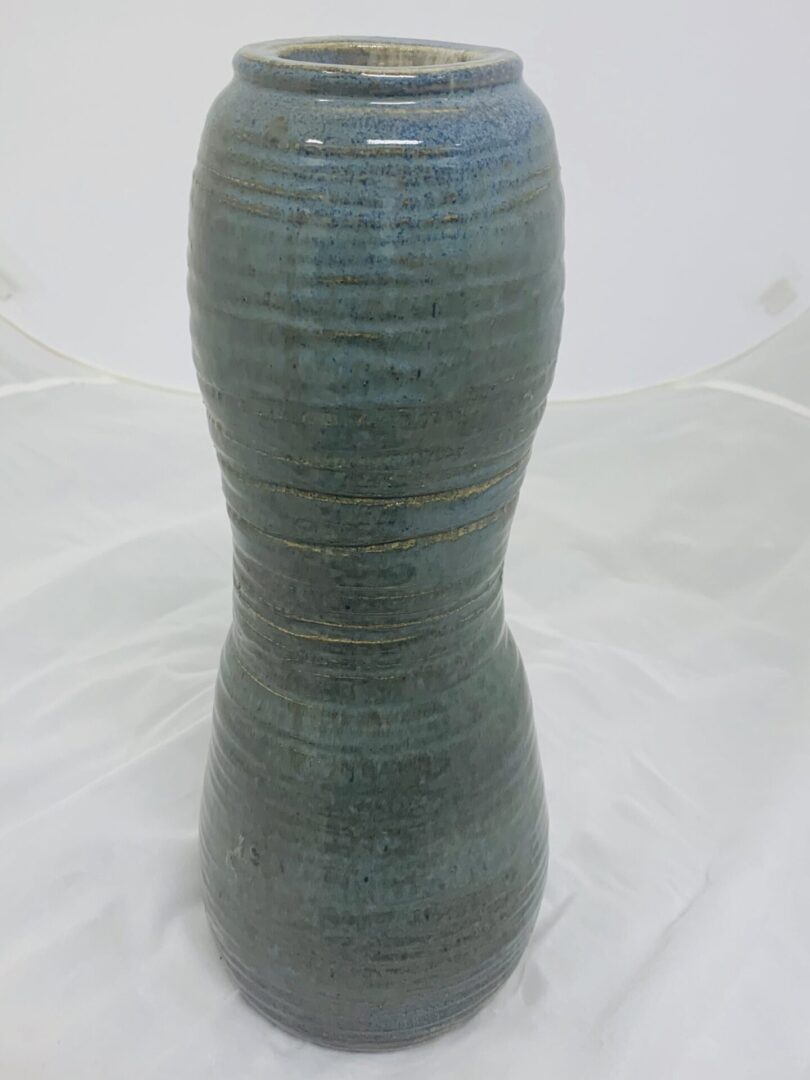 A tall, blue-gray ceramic vase with a textured surface.