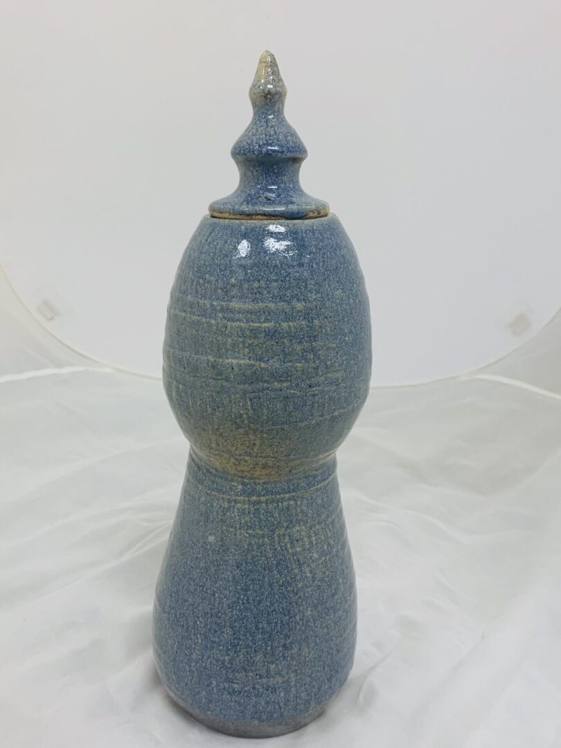 A blue ceramic decorative jar with a lid and finial on top.