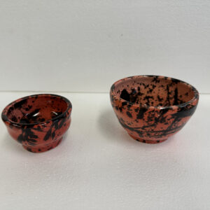 Two small red and black bowls with speckled patterns.