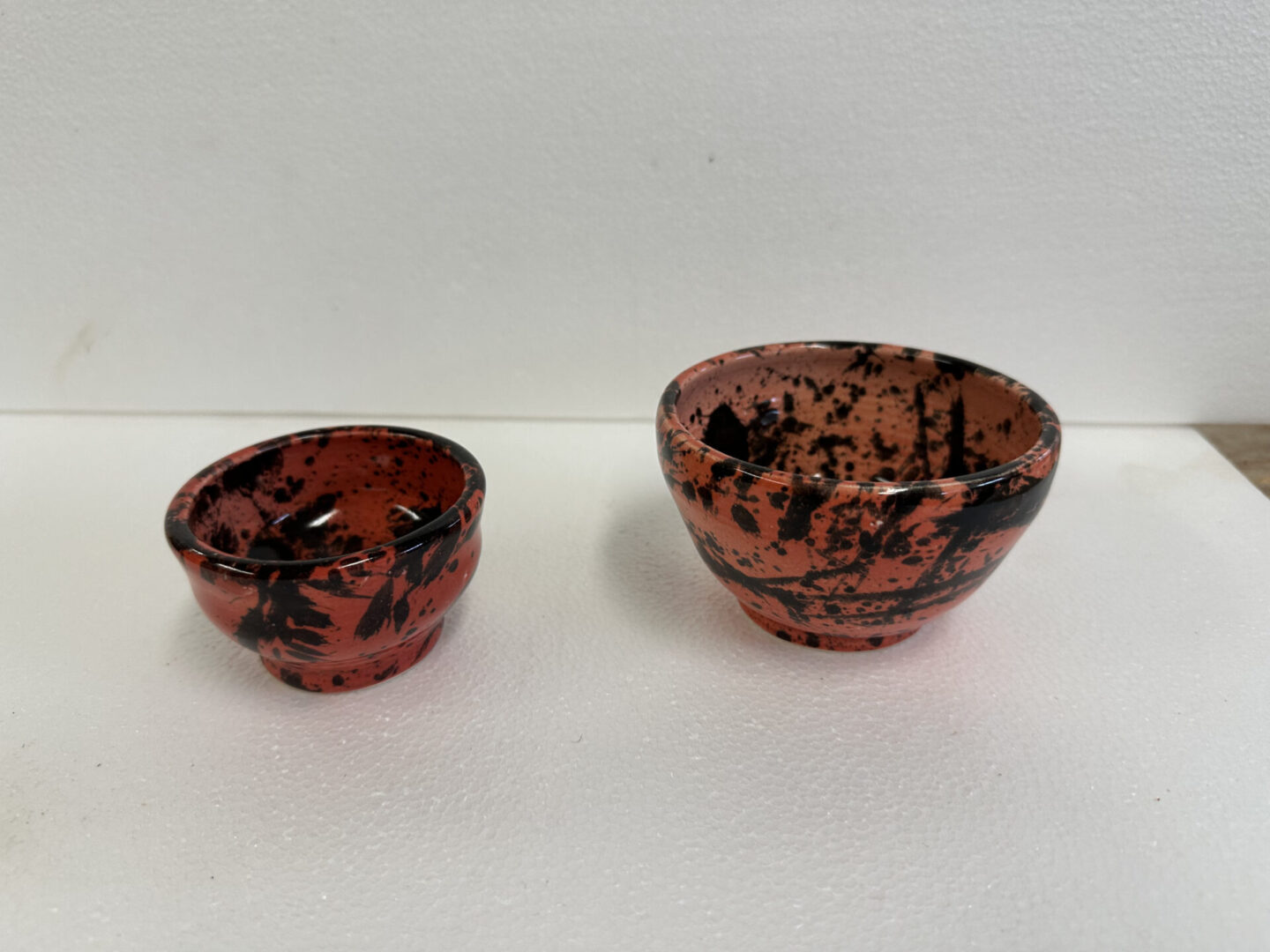 Two small red and black bowls with speckled patterns.