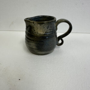 Handcrafted ceramic mug with a dark glaze and a rounded handle.