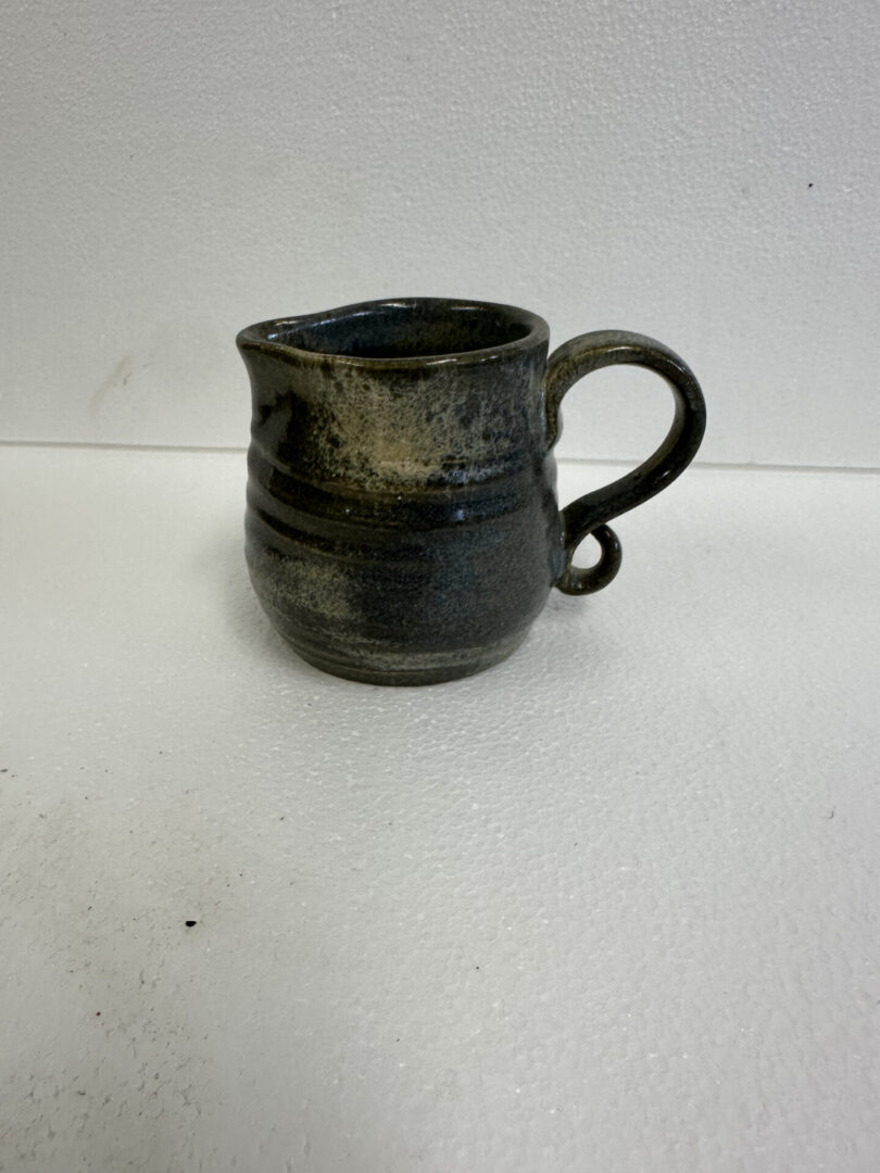 Handcrafted ceramic mug with a dark glaze and a rounded handle.
