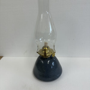 A vintage oil lamp with a glass chimney and dark base.