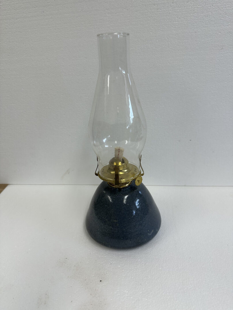 A vintage oil lamp with a glass chimney and dark base.