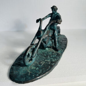 Bronze sculpture of a person riding a chopper-style bicycle.