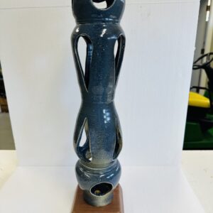 Tall ceramic sculpture with abstract human features and a hollow base.