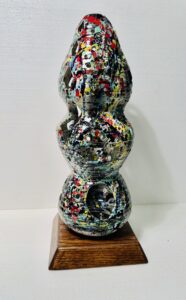 Abstract multicolored sculpture with rounded shapes on a wooden base.