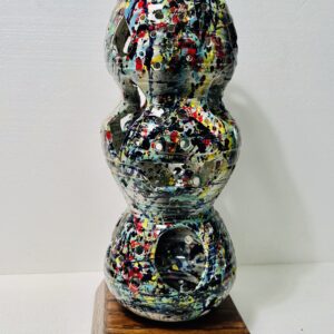 Abstract multicolored sculpture with rounded shapes on a wooden base.
