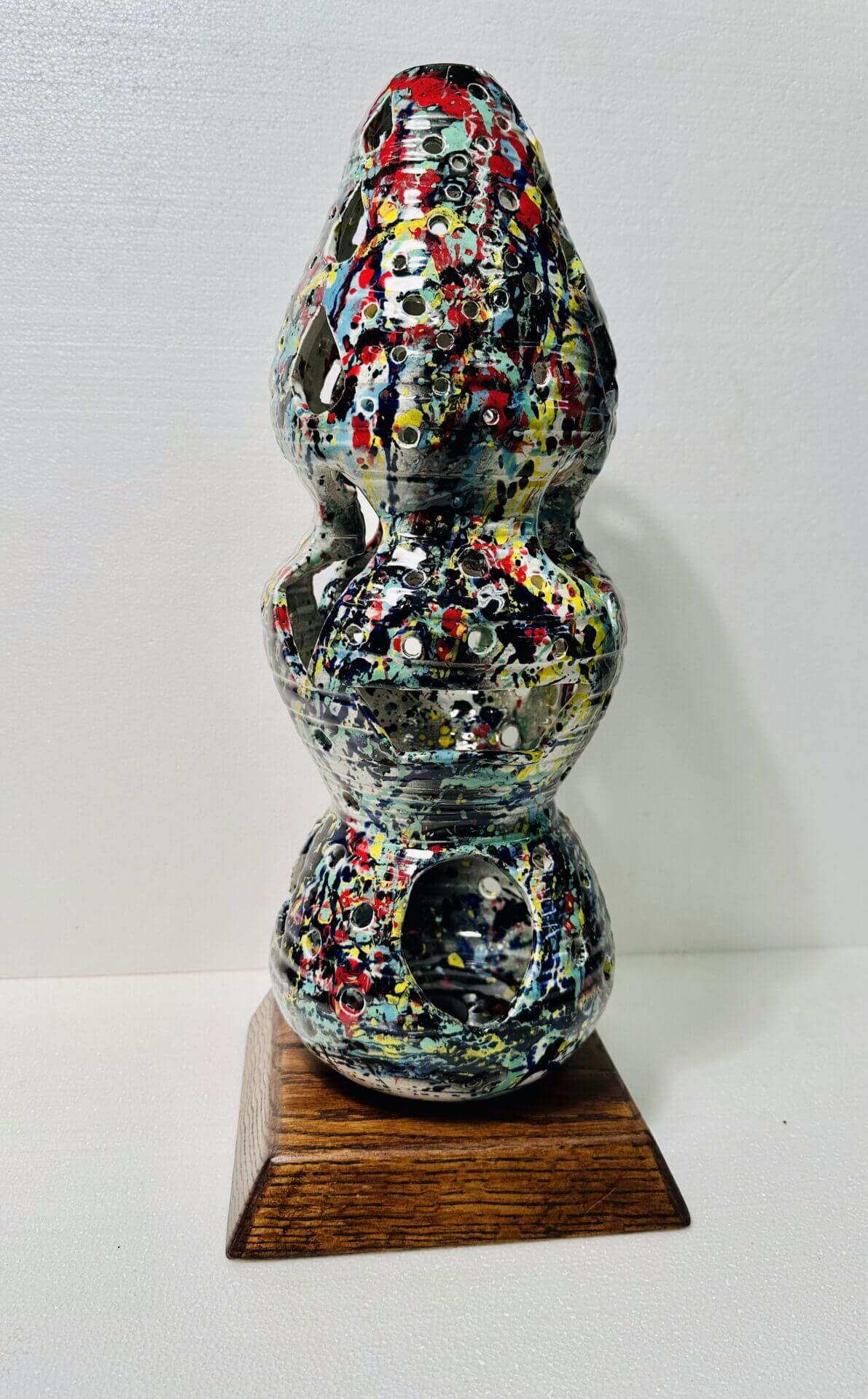 Abstract multicolored sculpture with rounded shapes on a wooden base.