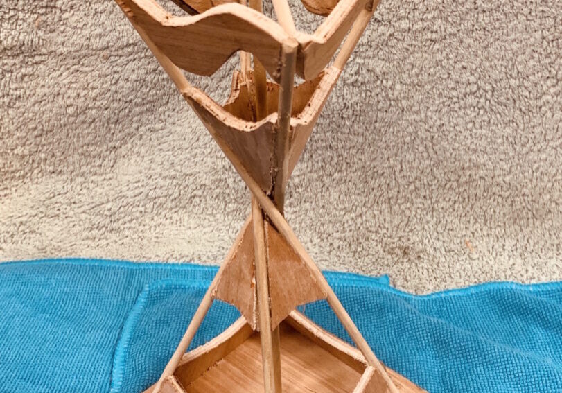 Wooden geometric sculpture with triangular shapes and a natural finish.