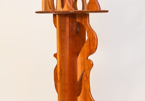 Tall wooden sculpture with intricate cutouts and geometric shapes.