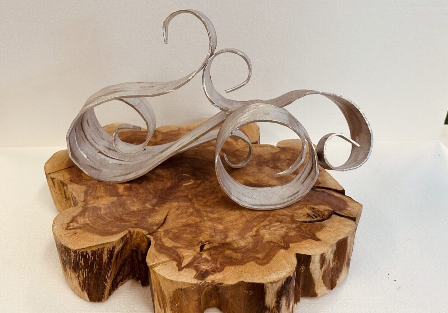 Elegant wooden sculptures with flowing, ribbon-like curves on a natural wood base.
