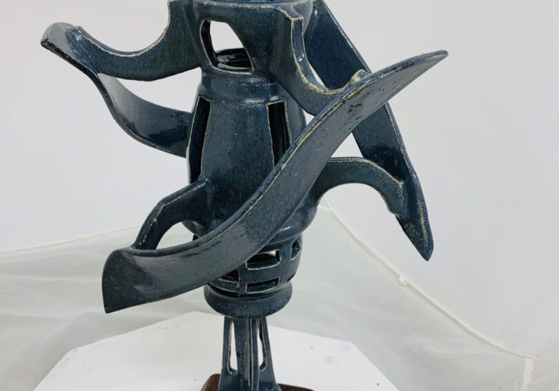 Abstract metal sculpture with dynamic curved elements on a wooden base.